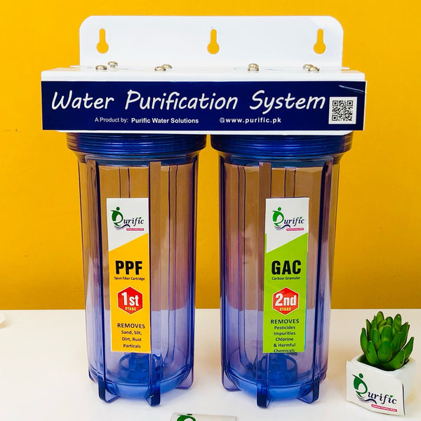 A two-stage water filtration system with clear blue filter housings and branding labels, mounted on a yellow background with a small green plant beside it.